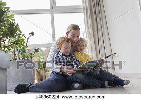 Mother reading to children (4-5, 8-9) in living room View Large Photo Image Picture - Mother reading to children (4-5, 8-9) in living room. Fotosearch