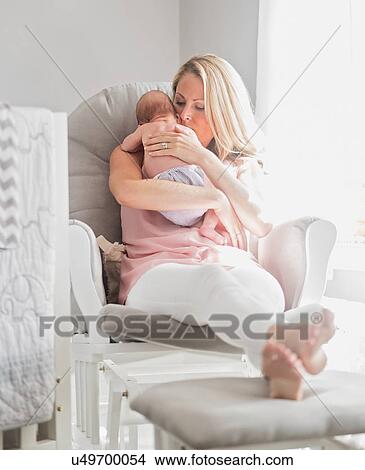 Picture - Mother sitting in armchair and holding baby son (0-1 months). Fotosearch