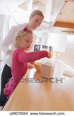 Mother watching daughter (4-5) taking out porridge from container View Large Photo Image Picture - Mother watching daughter (4-5) taking out porridge from container. Fotosearch