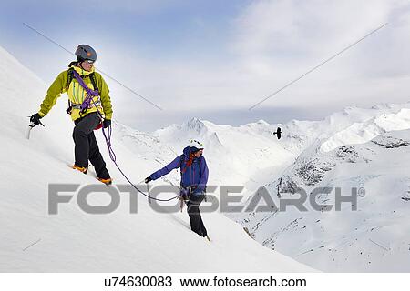 Stock Image - Mountaineers ascending snow-covered mountain, Saas Fee, Switzerland. Fotosearch