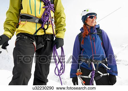 Stock Image - Mountaineers on snow-covered landscape looking away. Fotosearch