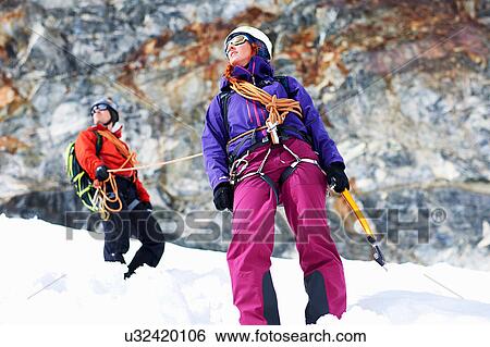 Stock Photograph - Mountaineers on snow-covered mountain looking away. Fotosearch