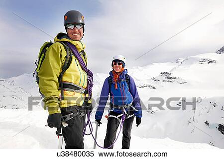 Stock Photography - Mountaineers on snow-covered mountain looking at camera smiling, Saas Fee, Switzerland. Fotosearch