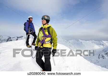 Stock Image - Mountaineers on top of snow-covered mountain looking away, Saas Fee, Switzerland. Fotosearch