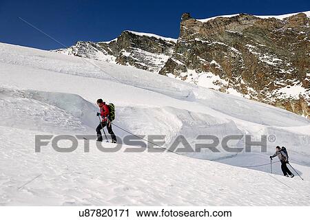 Stock Image - Mountaineers ski touring on snow-covered mountain, Saas Fee, Switzerland. Fotosearch
