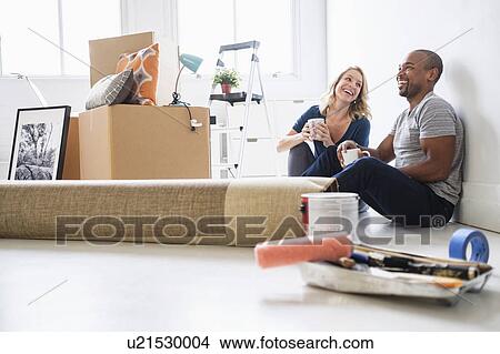 Picture - Multi ethnic couple in new apartment. Fotosearch