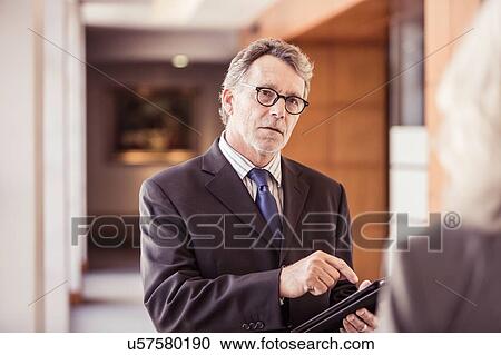 Over shoulder view of businessman using digital tablet in office corridor View Large Photo Image Stock Image - Over shoulder view of businessman using digital tablet in office corridor. Fotosearch