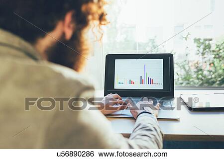 Over shoulder view of young man typing on laptop in office View Large Photo Image Stock Photograph - Over shoulder view of young man typing on laptop in office. Fotosearch