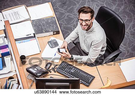 Overhead view of businessman using smartphone at office desk View Large Photo Image Picture - Overhead view of businessman using smartphone at office desk. Fotosearch