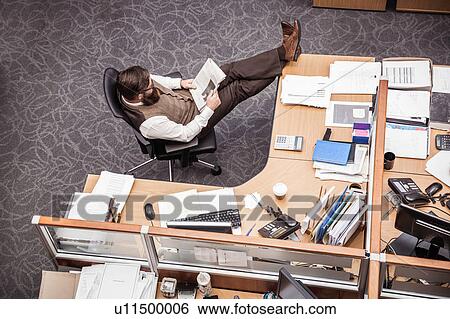 Overhead view of businessman with feet up on office desk View Large Photo Image Stock Photograph - Overhead view of businessman with feet up on office desk. Fotosearch