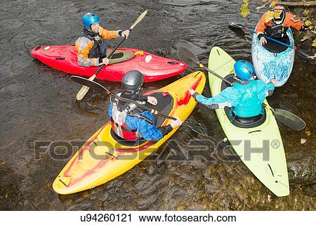 Stock Image - Overhead view of kayak team talking on river Dee. Fotosearch