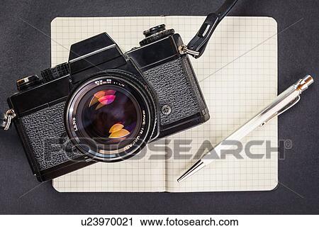 Stock Image - Overhead view of retro camera, notebook and pen. Fotosearch