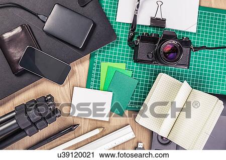 Stock Image - Overhead view of retro camera, notebook, diary, external hard drive, wallet, tripod and smartphone. Fotosearch