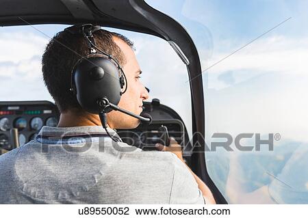 Stock Image - Pilot in cockpit of aircraft, in flight. Fotosearch