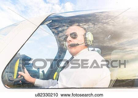 Stock Image - Pilot in cockpit of aircraft. Fotosearch