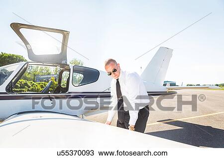 Stock Image - Pilot inspecting aircraft before flight. Fotosearch