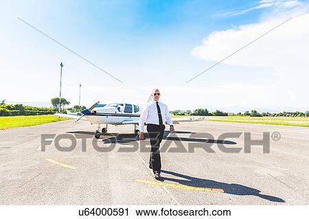 Stock Image - Pilot walking away from aircraft. Fotosearch