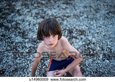 Stock Photo - Portrait of bare-chested boy wearing shorts looking at camera. Fotosearch