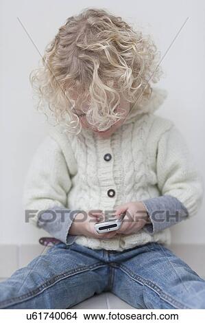 Picture - Portrait of blond girl (4-5) playing with mobile phone. Fotosearch
