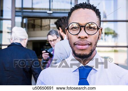 Stock Image - Portrait of businessman outside office building. Fotosearch