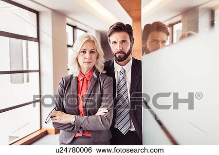 Stock Photograph - Portrait of businesswoman and businessman at office doorway. Fotosearch