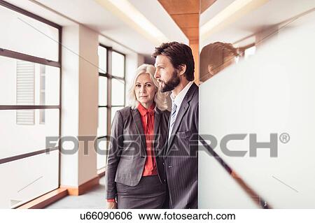 Portrait of businesswoman and businessman looking out of office window View Large Photo Image Stock Photograph - Portrait of businesswoman and businessman looking out of office window. Fotosearch