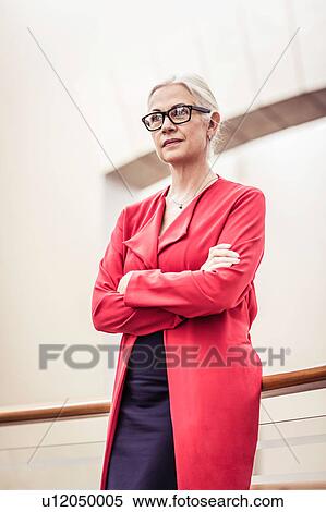 Stock Photography - Portrait of businesswoman with arms folded on office balcony. Fotosearch