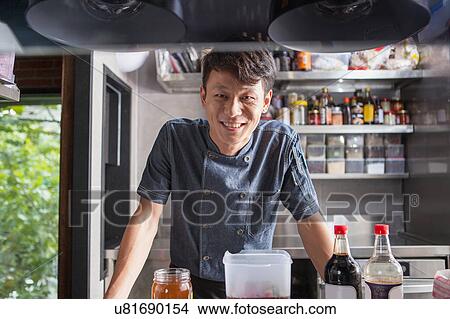 Picture - Portrait of chef in commercial kitchen looking at camera smiling. Fotosearch