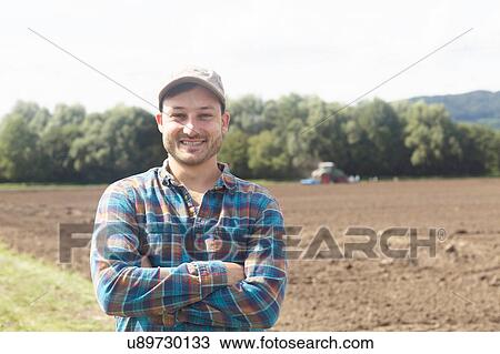 Stock Image - Portrait of farmer looking at camera, arms crossed smiling. Fotosearch