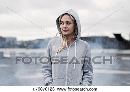Stock Image - Portrait of female runner in hoody on stormy dockside. Fotosearch