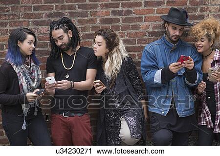 Portrait of friends using smartphones against brick wall View Large Photo Image Stock Image - Portrait of friends using smartphones against brick wall. Fotosearch