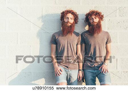 Stock Photography - Portrait of identical adult male twins with red hair and beards against wall. Fotosearch