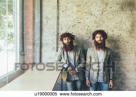 Stock Photography - Portrait of identical male hipster twins in office. Fotosearch