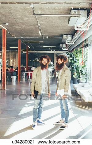Portrait of male adult hipster twins holding digital tablet and laptop in office View Large Photo Image Stock Image - Portrait of male adult hipster twins holding digital tablet and laptop in office. Fotosearch