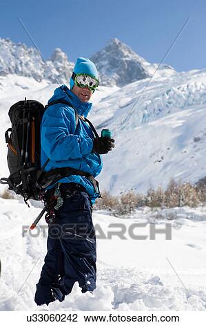 Stock Image - Portrait of male snowboarder wearing ski goggles in deep snow, Trient, Swiss Alps, Switzerland. Fotosearch