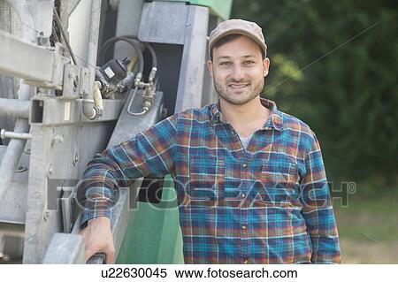 Stock Photography - Portrait of man leaning against truck looking at camera smiling. Fotosearch