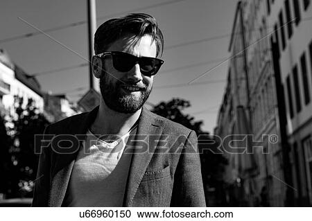 Stock Image - Portrait of man wearing blazer and sunglasses smiling, Berlin, Germany. Fotosearch