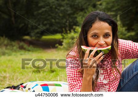 Portrait of mature woman outdoors, sitting in field, eating watermelon View Large Photo Image Stock Photograph - Portrait of mature woman outdoors, sitting in field, eating watermelon. Fotosearch