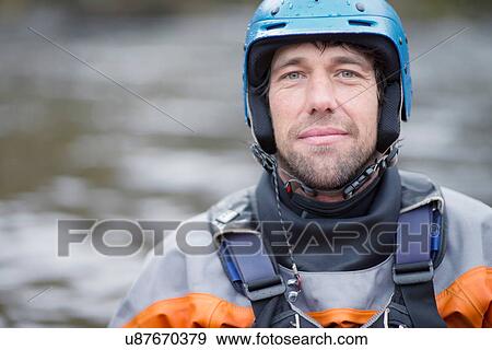 Stock Photo - Portrait of mid adult male kayaker in watersports helmet. Fotosearch
