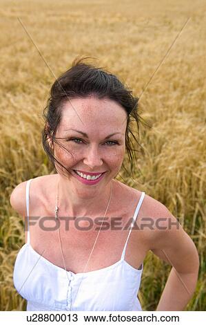 Portrait of mid adult woman standing in field, smiling View Large Photo Image Stock Image - Portrait of mid adult woman standing in field, smiling. Fotosearch