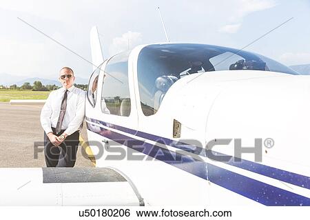 Stock Photograph - Portrait of pilot standing beside aircraft. Fotosearch