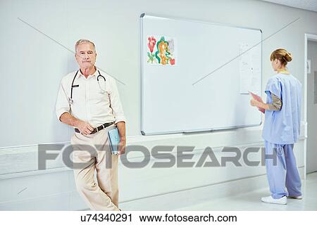 Stock Image - Portrait of senior doctor in hospital ward. Fotosearch