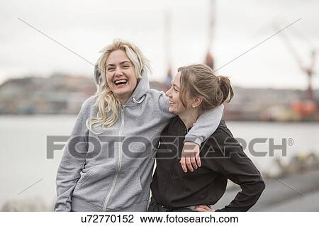 Stock Image - Portrait of two female runner friends laughing on dockside. Fotosearch