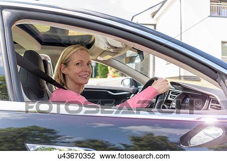 Portrait of woman driving electric car View Large Photo Image Stock Image - Portrait of woman driving electric car. Fotosearch
