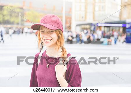 Stock Photo - Portrait of woman wearing baseball cap looking at camera smiling, London, UK. Fotosearch