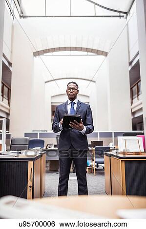 Stock Photograph - Portrait of young businessman using digital tablet in office. Fotosearch