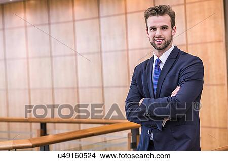 Portrait of young businessman with arms folded on office balcony View Large Photo Image Picture - Portrait of young businessman with arms folded on office balcony. Fotosearch