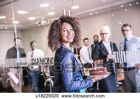 Portrait of young businesswoman carrying celebration cake into boardroom View Large Photo Image Stock Image - Portrait of young businesswoman carrying celebration cake into boardroom. Fotosearch
