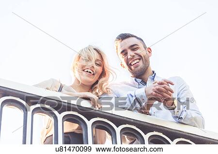Stock Photo - Portrait of young couple looking down from bridge. Fotosearch