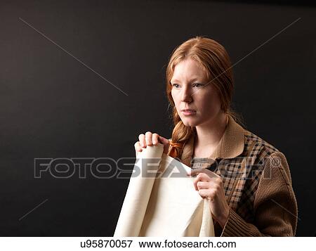 Stock Photo - Portrait of young female designer holding rolled fabric. Fotosearch